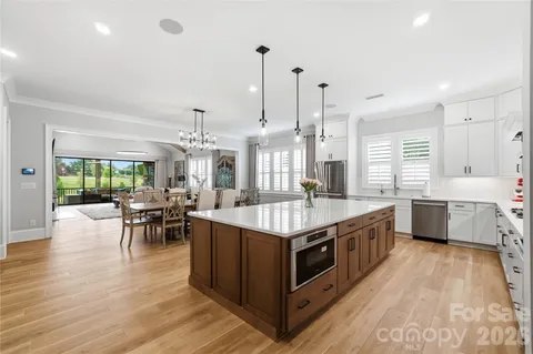 a large kitchen with kitchen island a large island a sink a stove and a wooden floors