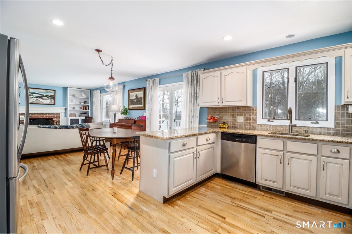 52 Key Rock Road Newtown, CT 06470 - Photo 5 of 40 a kitchen with stainless steel appliances granite countertop a stove top oven a sink dishwasher a dining table and chairs with wooden floor