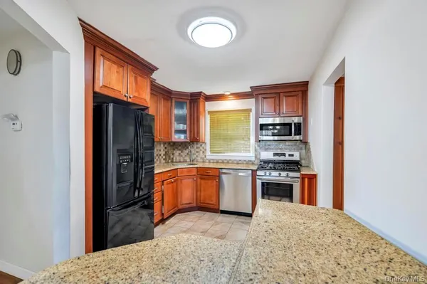 a kitchen with stainless steel appliances granite countertop a refrigerator a stove and a sink with cabinets