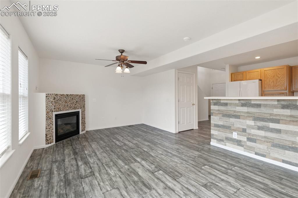 5679 Sunshade Point Colorado Springs, CO 80923 - Photo 5 of 30 a view of empty room with wooden floor and fireplace