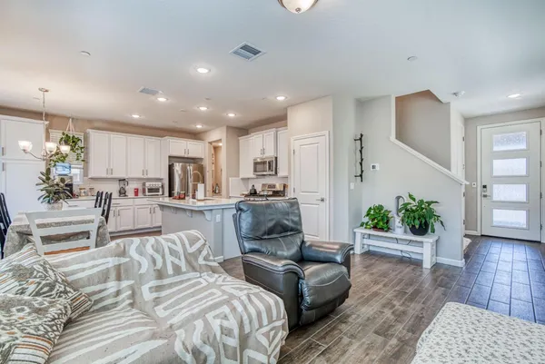 a living room with furniture wooden floor and a kitchen