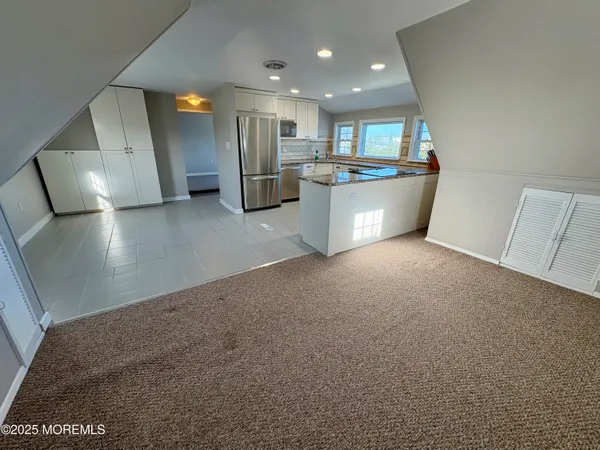 a view of a kitchen with refrigerator and white cabinets