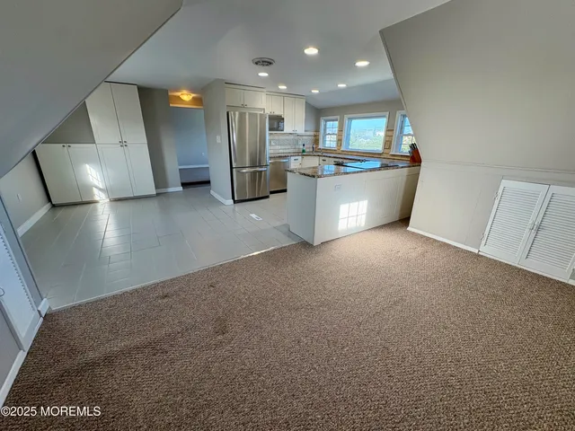 a view of a kitchen with refrigerator and white cabinets