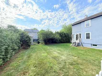 a backyard of a house with plants and large tree