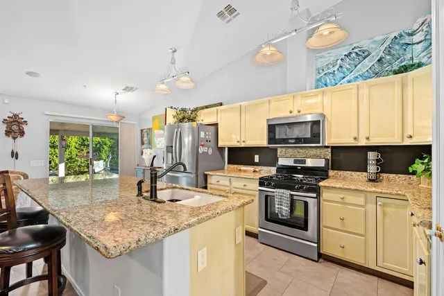 a kitchen with stainless steel appliances kitchen island granite countertop a stove a sink and a microwave