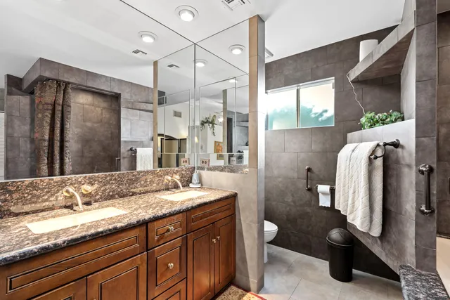 a bathroom with a granite countertop sink a toilet and a mirror