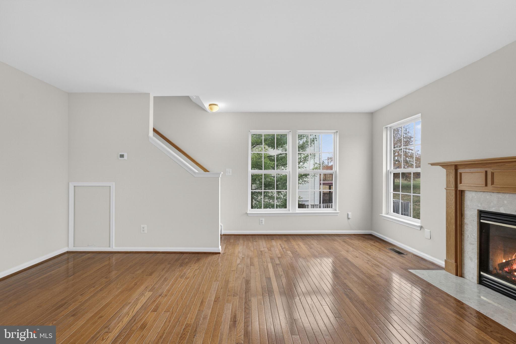 6741 Stone Maple Terrace Centreville, VA 20121 - Photo 12 of 24 an empty room with wooden floor fireplace and windows