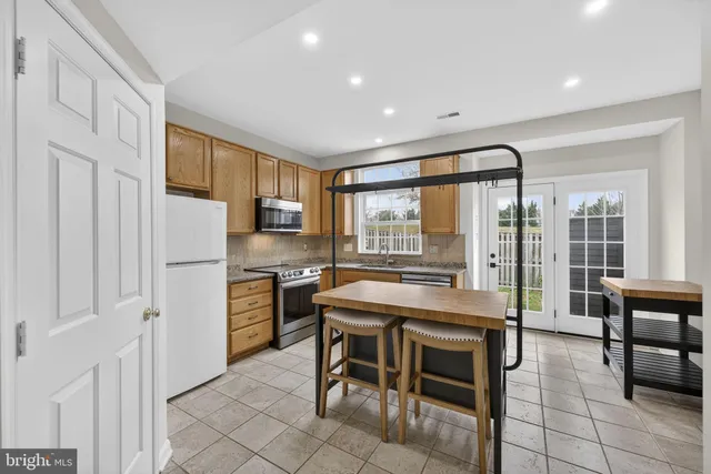 a kitchen with stainless steel appliances granite countertop dining table chairs sink and cabinets