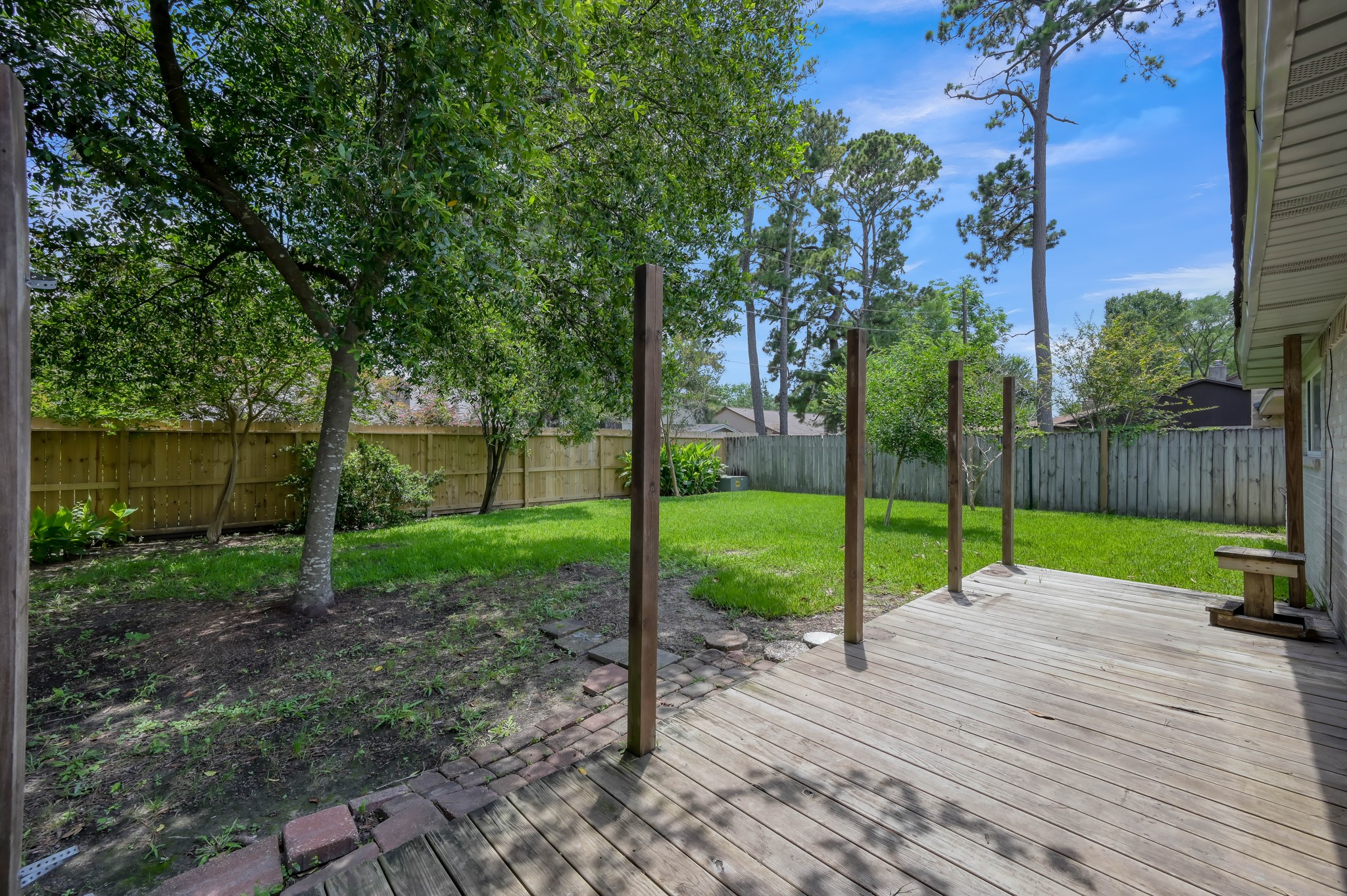 4314 Enchantedgate Drive Spring, TX 77373 - Photo 36 of 47 Backyard features a spacious wooden deck overlooking a lush, fenced-in lawn with mature trees, providing a private and serene outdoor space.