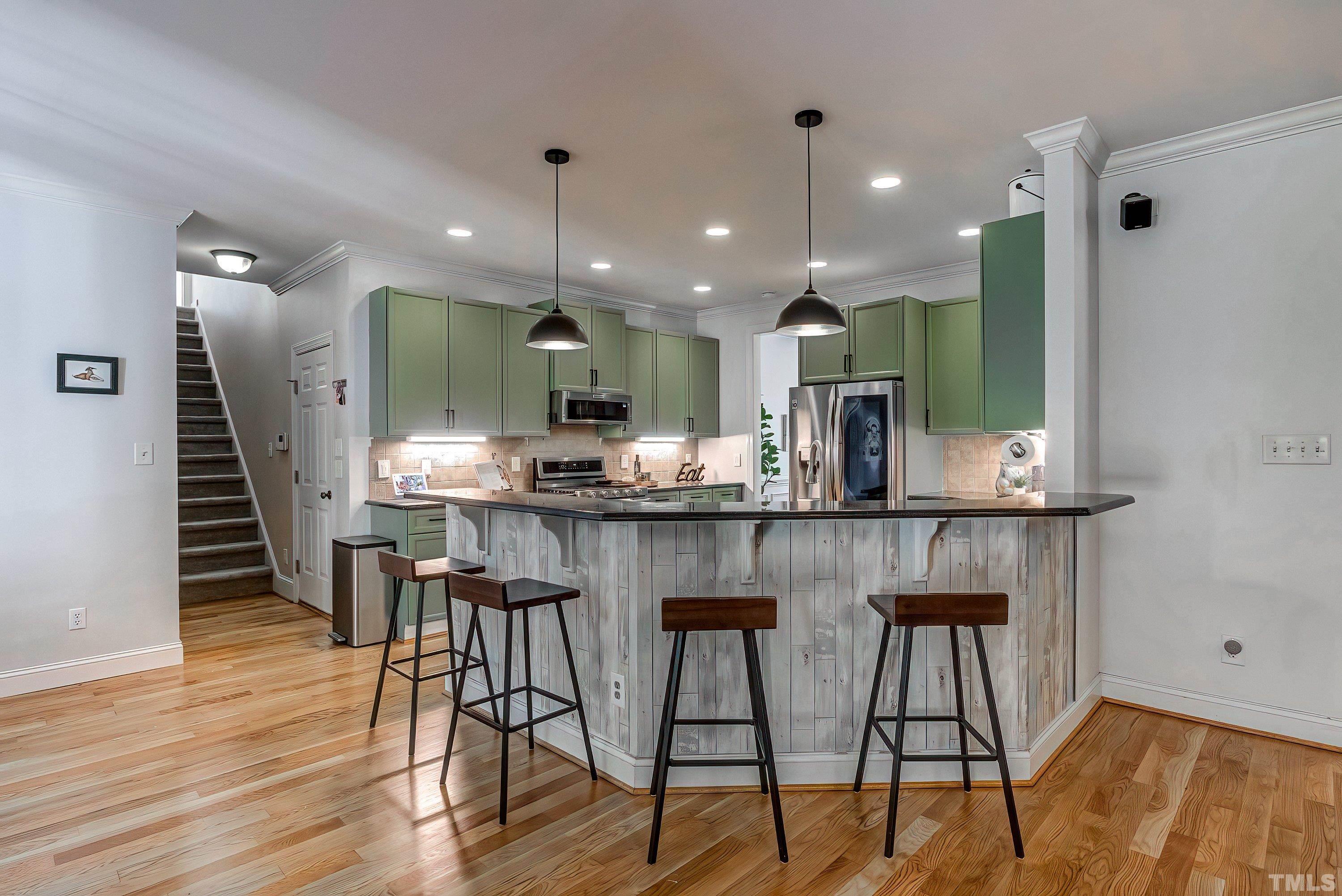 1613 Strategy Way Wake Forest, NC 27587 - Photo 19 of 58 a kitchen with stainless steel appliances kitchen island granite countertop a table chairs sink and cabinets