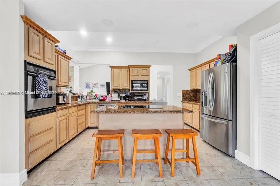 19905 Southwest 135th Avenue Miami, FL 33177 - Photo 6 of 34 a kitchen with stainless steel appliances granite countertop a refrigerator and a stove top oven