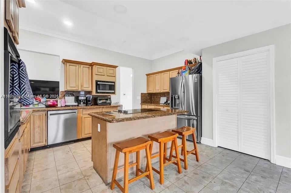 19905 Southwest 135th Avenue Miami, FL 33177 - Photo 10 of 34 a kitchen with stainless steel appliances granite countertop a refrigerator and a stove top oven