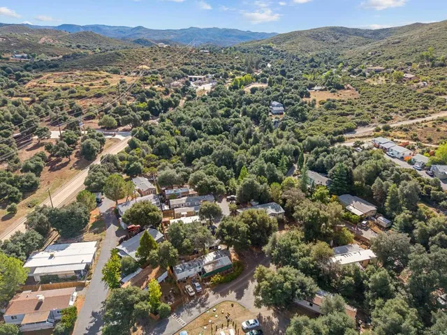 an aerial view of residential houses with outdoor space and trees