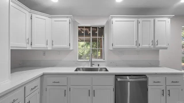 a kitchen with stainless steel appliances granite countertop white cabinets and a sink