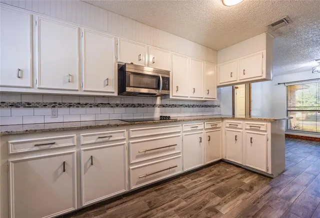 a kitchen with granite countertop white cabinets white stainless steel appliances with a sink and dishwasher