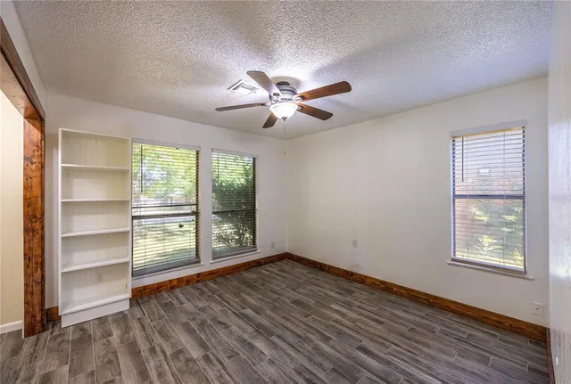 a view of an empty room with a window and wooden floor