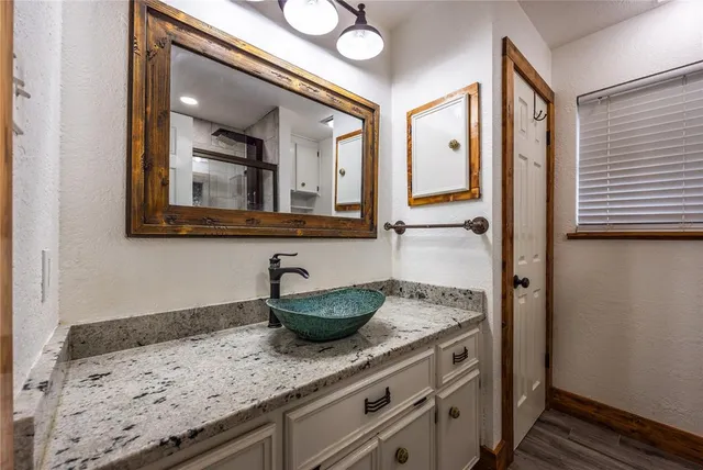 a bathroom with a granite countertop sink and a mirror