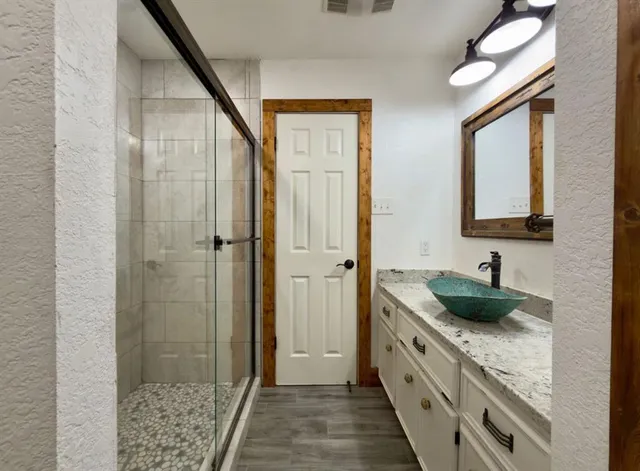a spacious bathroom with a granite countertop sink a mirror and shower