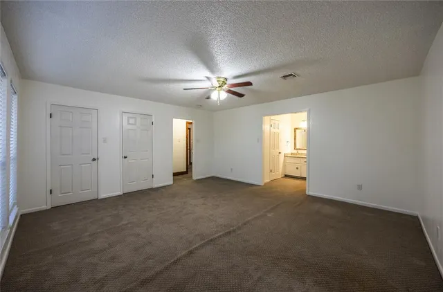 an empty room with windows and fan