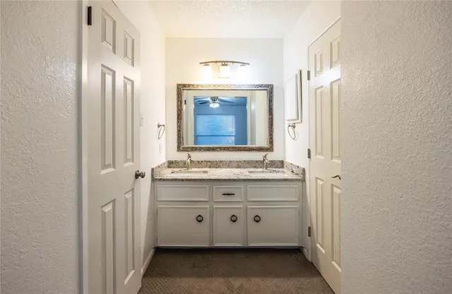 a bathroom with a granite countertop sink a toilet and a mirror