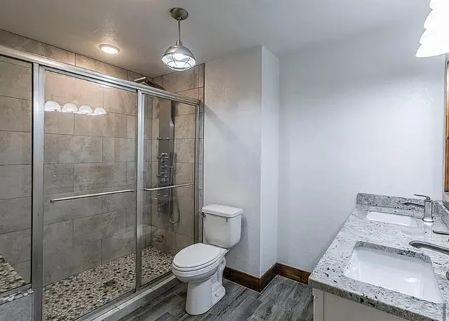 a bathroom with a granite countertop sink a toilet and shower