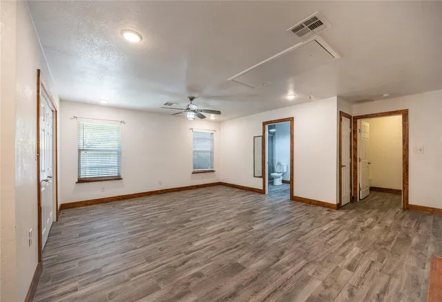 a view of an empty room with window and wooden floor