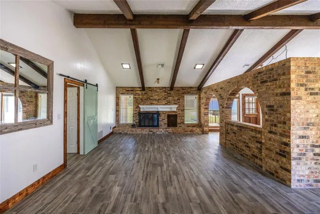 a view of an empty room with wooden floor fireplace and a window