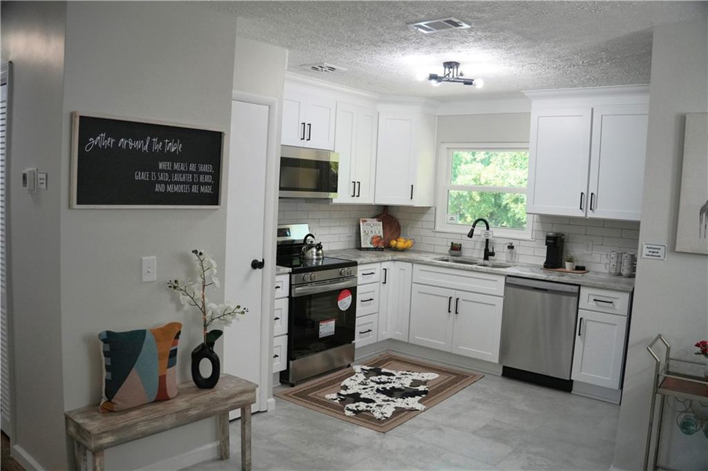 145 Beaverdam Road Winterville, GA 30683 - Photo 13 of 53 a kitchen with stainless steel appliances kitchen island granite countertop a sink dishwasher a stove a refrigerator a microwave oven with white cabinets and wooden floor