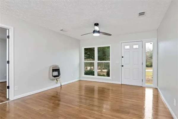 a view of an empty room with a window and wooden floor