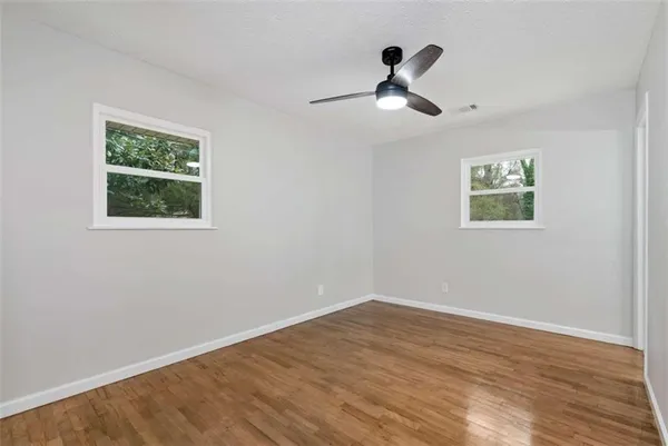 a view of empty room with wooden floor and fan