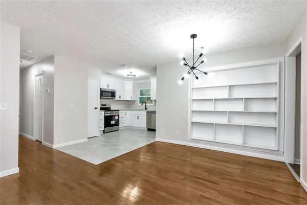 a view of a kitchen with kitchen island wooden floor and stainless steel appliances