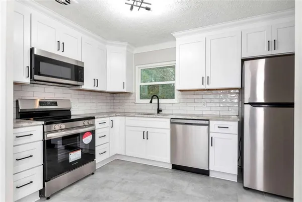 a kitchen with white cabinets stainless steel appliances and sink