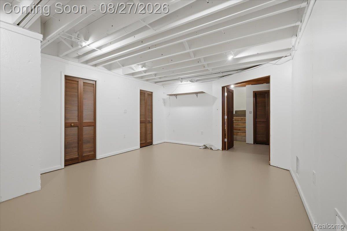 10100 Springtime Circle Clarkston, MI 48348 - Photo 54 of 73 Spacious room with smooth flooring, white walls, exposed ceiling joists, and multiple louvered bifold doors