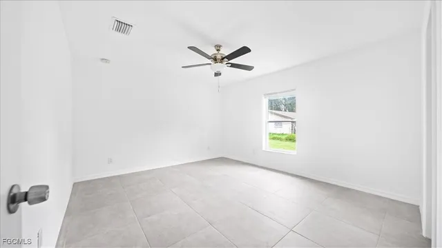 an empty room with windows and fan