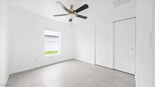 an empty room with a window and a ceiling fan