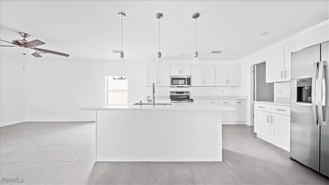 a kitchen with stainless steel appliances a refrigerator a stove and white cabinets