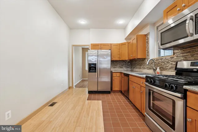 a kitchen with stainless steel appliances granite countertop a stove a sink and a microwave