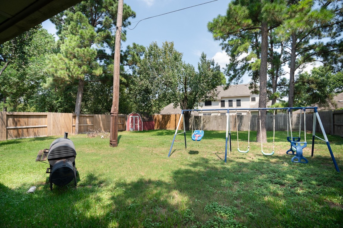 17426 Colony Creek Drive Spring, TX 77379 - Photo 21 of 26 a view of a backyard with a slide trees and wooden fence
