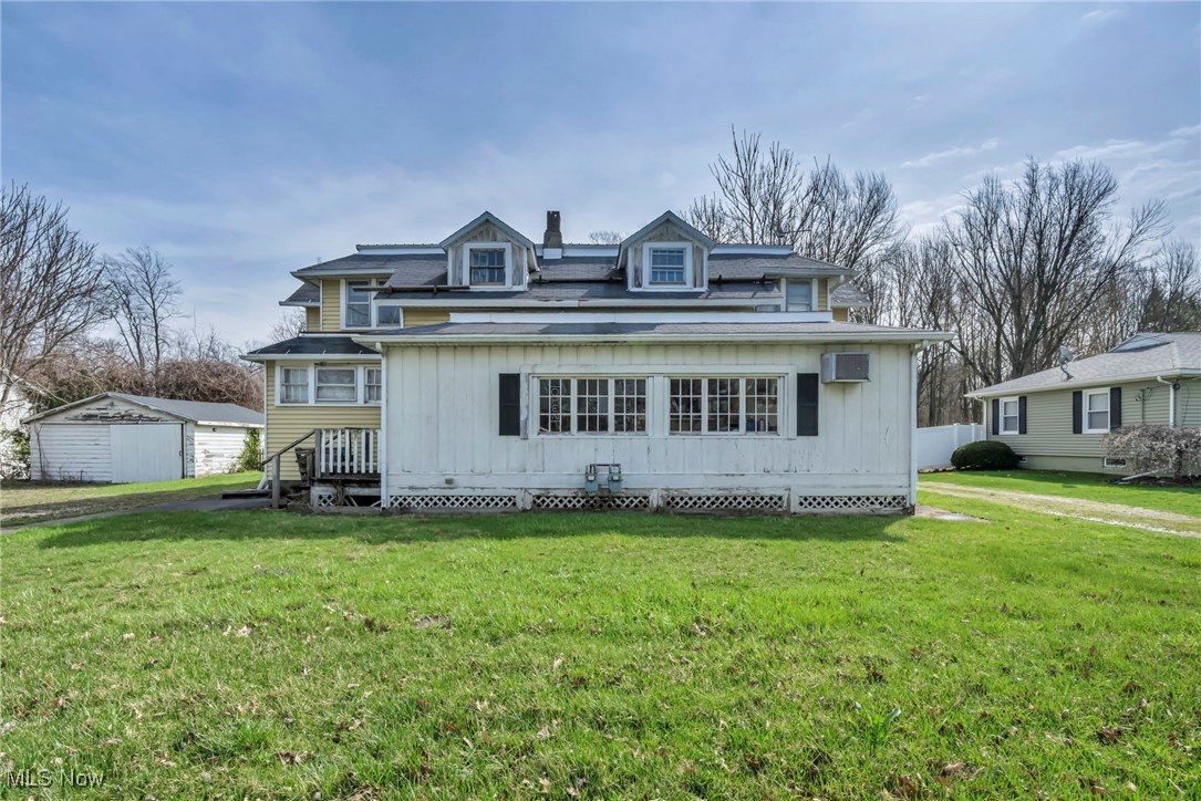 View of front of house featuring roof with shingles, a wall mounted AC, and a front lawn