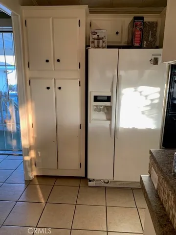 a view of a refrigerator in kitchen and an empty room