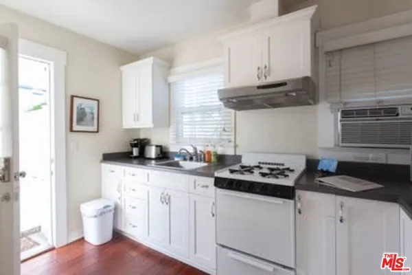 a kitchen with stainless steel appliances a white stove a sink dishwasher and cabinets with wooden floor