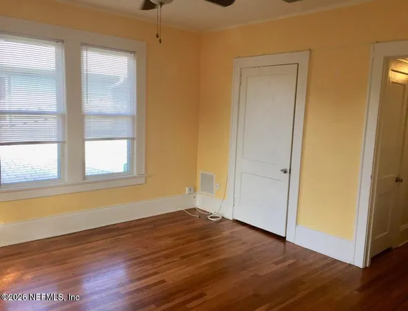 a view of empty room with wooden floor and fan