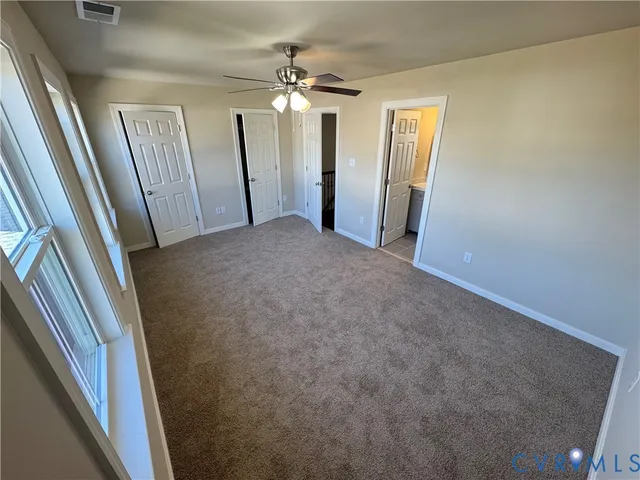 en empty room with windows and ceiling fan