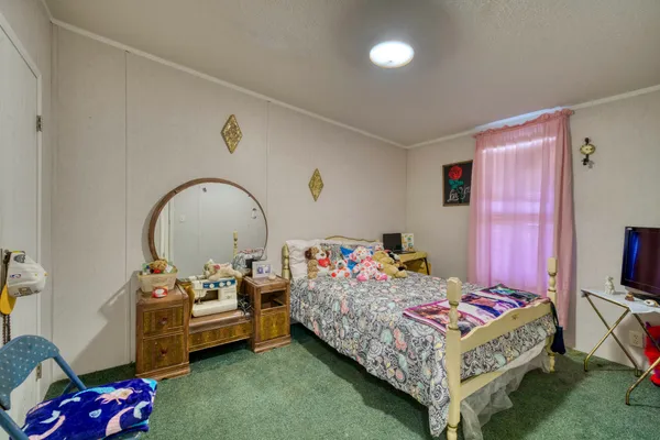 a bedroom with bed and a flat tv screen on the dresser