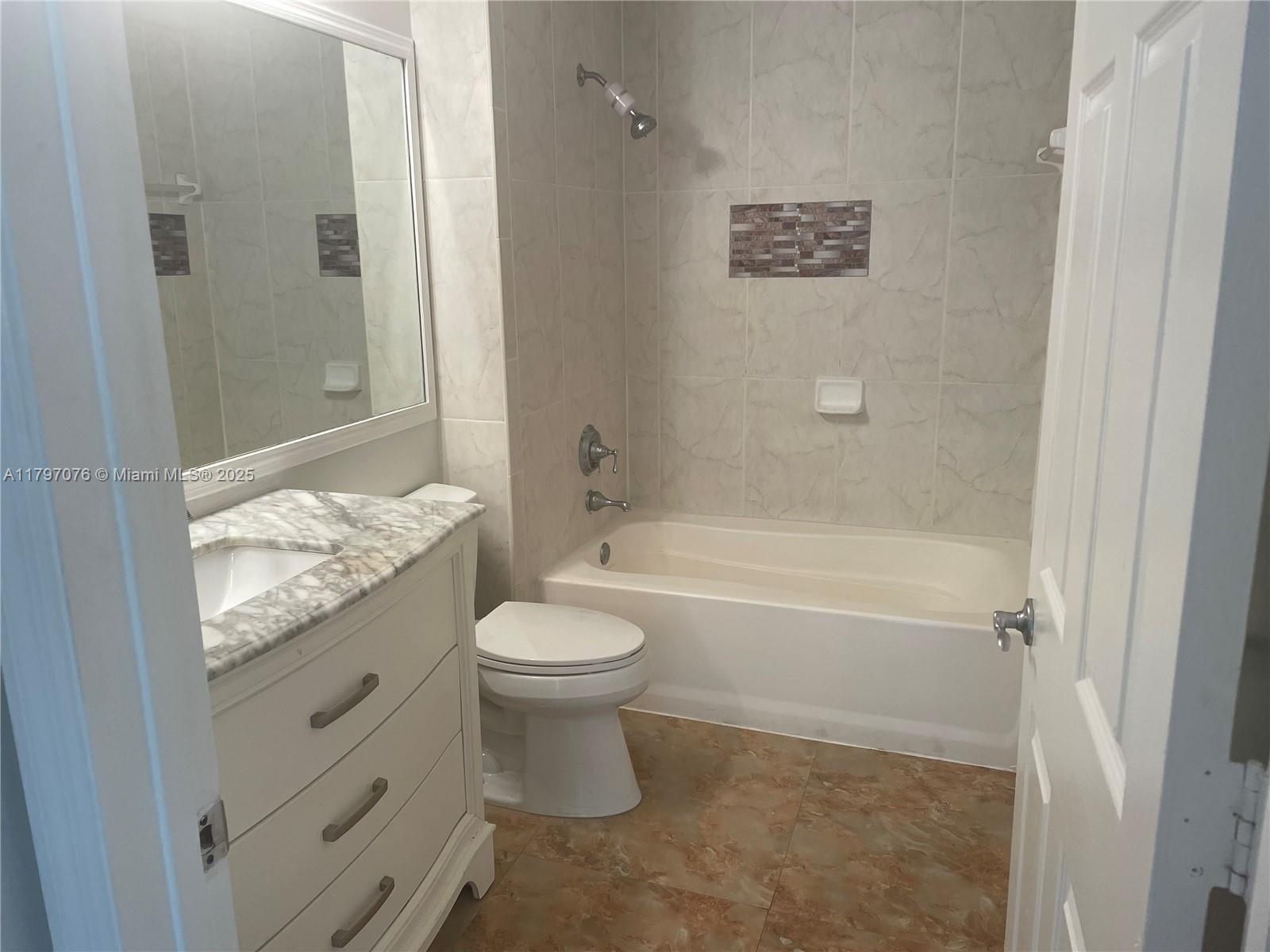 Glenvar Heights Miami, FL 33155 - Photo 7 of 10 a bathroom with a granite countertop toilet a sink and a bathtub