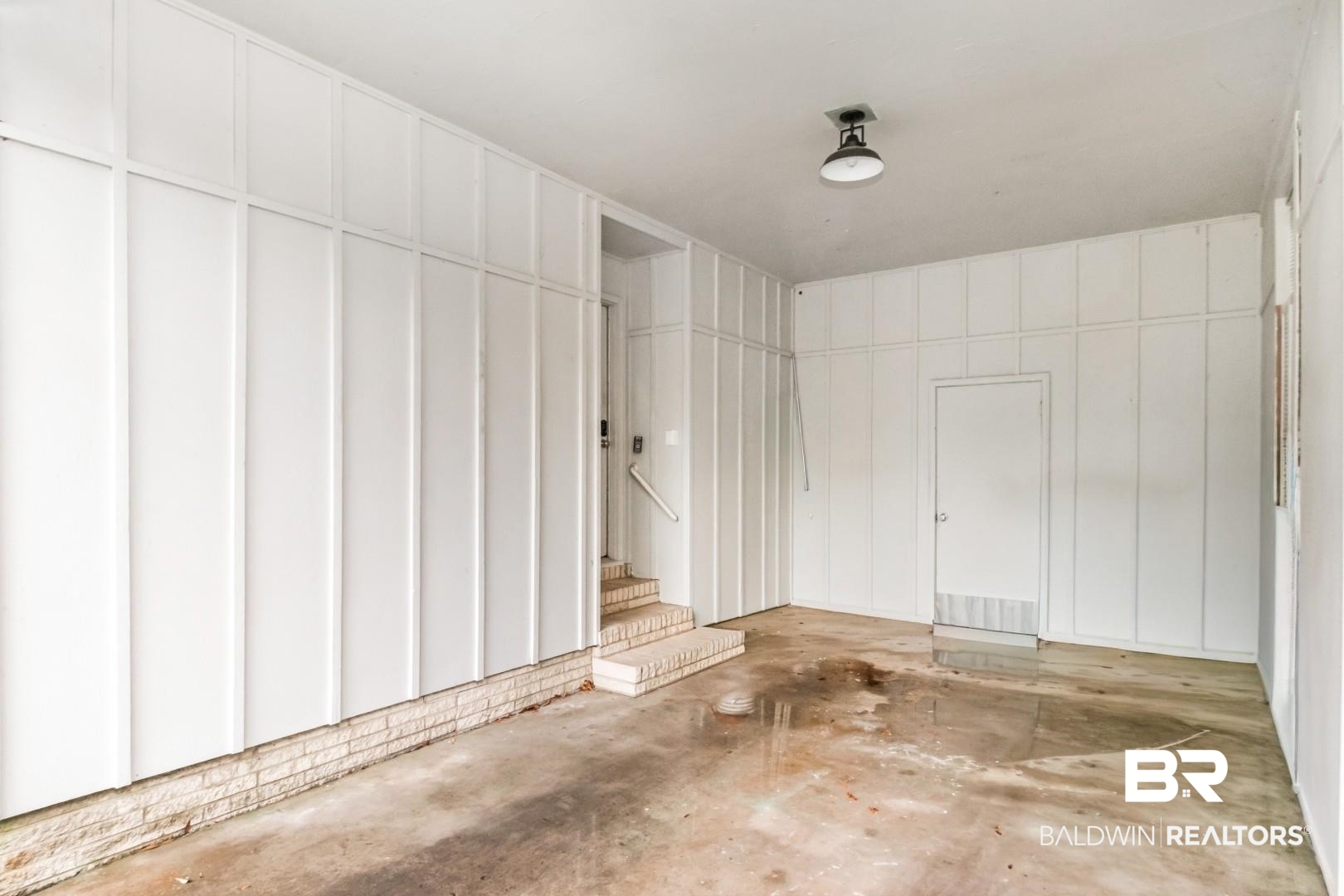 4596 Hawthorne Place Mobile, AL 36608 - Photo 25 of 34 Utility space featuring board and batten style walls, a single ceiling-mounted light fixture, a brick foundation element, and a side entry door with steps