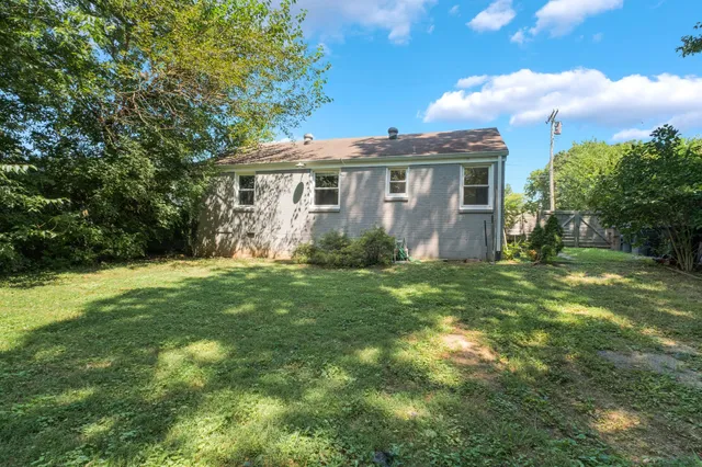 a view of a yard in front of a house with large windows