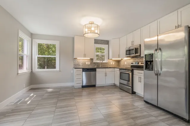 a kitchen with stainless steel appliances granite countertop a refrigerator a sink a stove a microwave and island