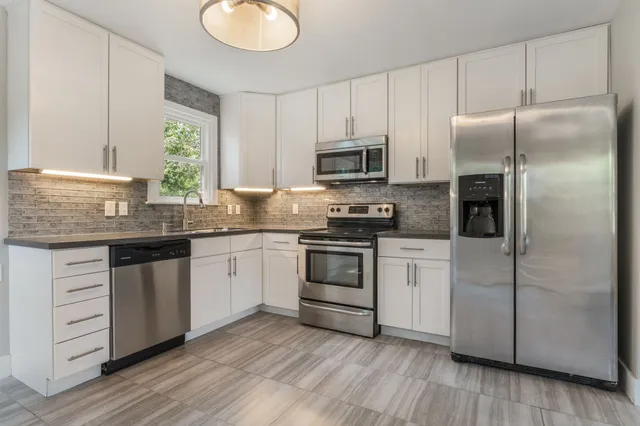 a kitchen with a refrigerator stove and white cabinets