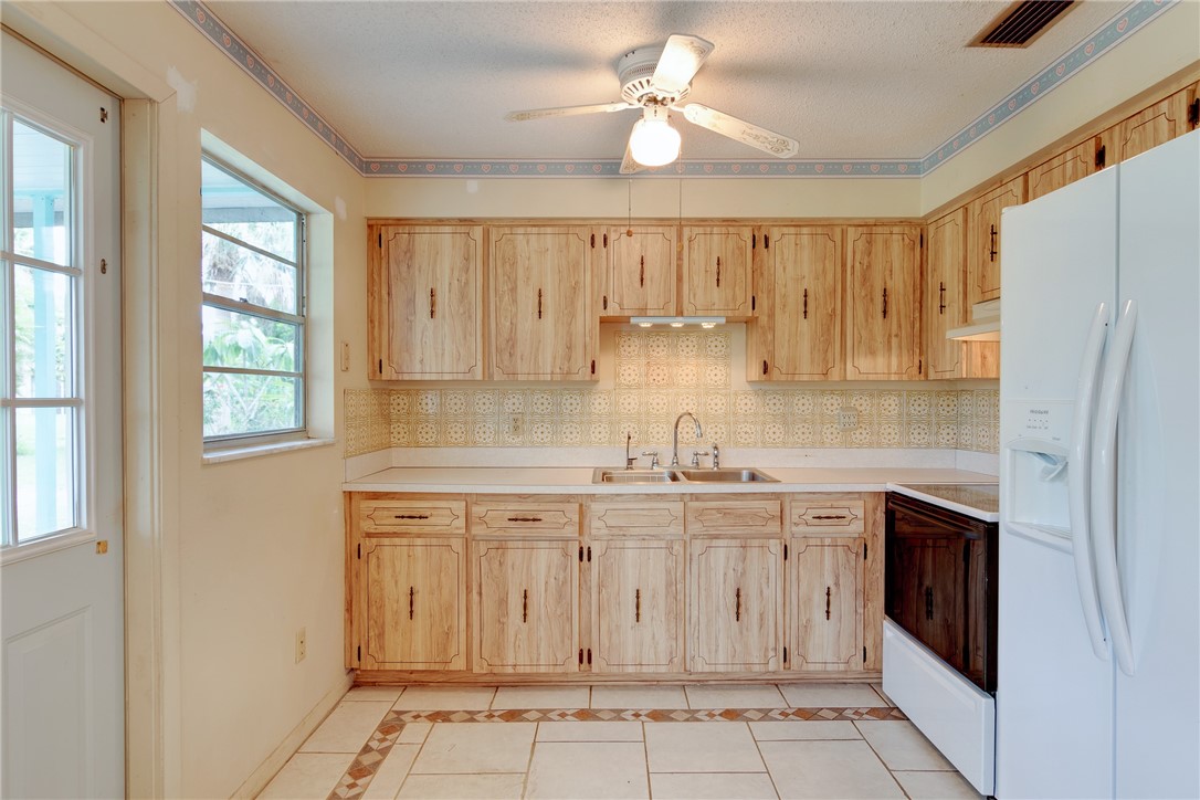 325 Perch Lane Sebastian, FL 32958 - Photo 9 of 26 a kitchen with stainless steel appliances granite countertop a sink a stove a refrigerator a microwave oven with cabinets and wooden floor